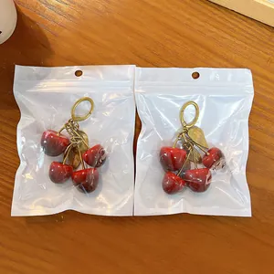 Portachiavi a forma di ciliegia rossa con foglie dorate in confezione trasparente