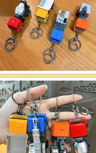 Set di quattro portachiavi colorati a forma di camion da cantiere su fondo legno e in mano