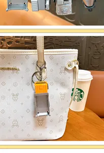 Dettaglio del portachiavi a forma di camion giallo appeso a una borsa bianca
