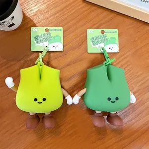 Pair of cute green onion shaped silicone coin purse keychain charms on a wooden surface