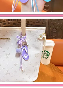 Detailed view of a cute purple slipper keychain with a fur ball and plaid bow