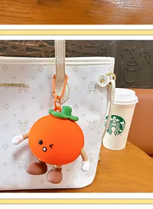 Close-up view of a cute orange fruit character keychain accessory hanging on a white handbag.