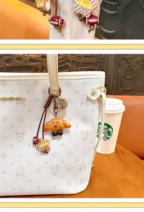 Detail of a cute croissant-shaped bag charm with a smiley face hanging on a white tote bag