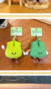Detail of creative green onion shaped coin purses with cute cartoon limbs on a wooden table.