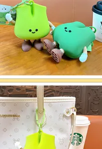 Close-up of cute green scallion coin purse charm hanging on a stylish handbag