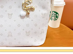 Close-up detail of gold balloon dog pendant with white pearls on a monogram tote bag