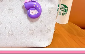 Detailed macro view of a creative purple music snail keychain hanging on a stylish white bag