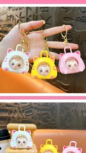 Detail of cute cat space capsule keychains in white, yellow, and pink for bag charm.