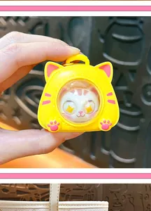Close-up of yellow cat space capsule keychain toy with cute white kitty figure