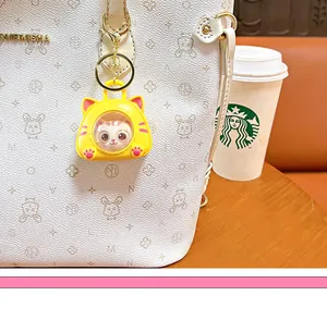 Cute cat space capsule keychain pendant hanging on a white handbag in lifestyle scene