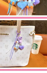 Close-up of a cute purple duck bag charm with heart and bow pendant on a tote