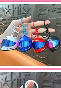 Detail view of four colorful mini motorcycle helmet keychains in white, blue, red, and black.
