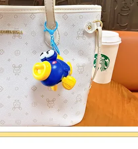 Close-up of a vibrant blue and yellow wind-up jumping fish keychain on a white bag