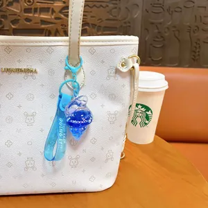 Blue seashell liquid-filled keychain with ocean dolphin and starry glitters on white bag
