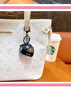 Detailed view of light-up mini helmet keychain accessory on a white patterned tote bag