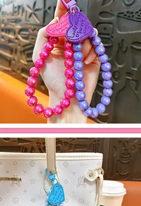 Close-up of colorful beaded heart pendants on a hand and hanging on a stylish white handbag