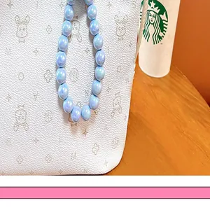 Macro detail of light blue AB pearlescent beads on a bag with character patterns
