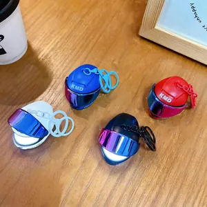 Quattro portachiavi a forma di casco da moto luminosi e colorati su un tavolo di legno