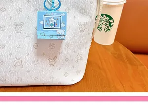 Close-up of a blue cartoon bear fidget toy keychain hanging on a white patterned bag