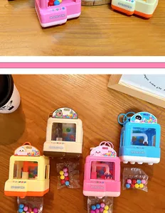 Vue détaillée de mini porte-clés machine à pince colorés en rose, bleu et jaune pastel.