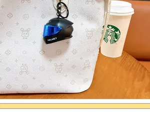Dettaglio ravvicinato di un portachiavi a forma di casco da moto luminoso su una borsa