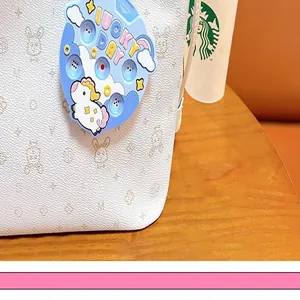 Close-up of a blue unicorn dice machine keychain charm attached to a white textured bag