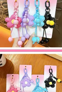 Dettaglio di ciondoli per borsa a forma di fiore in rosa, viola, blu e nero.