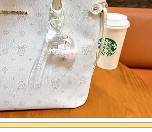 Detailed view of a cute sheep liquid keychain with flowing sand on a white bag