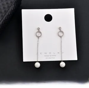 Detailed view of elegant long drop pearl earrings with 925 silver post on white display card