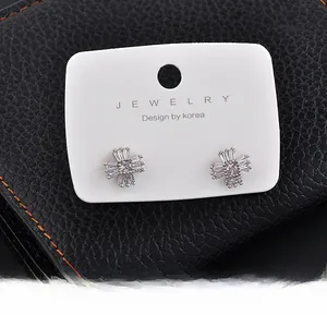 Detail of silver cross stud earrings with CZ on white jewelry display card
