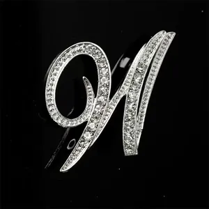 Primer plano de un elegante broche plateado con cristales brillantes en forma de letra M