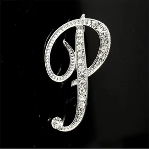 Detalle de elegante broche plateado letra P con brillantes pedrería de strass y cristal