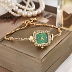 Detail einer eleganten goldenen Armbanduhr mit quadratischem grünem Zifferblatt