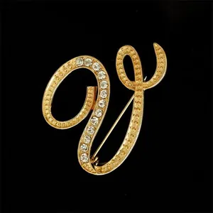 Detalle de un elegante broche de letra V dorada con diamantes de imitación brillantes