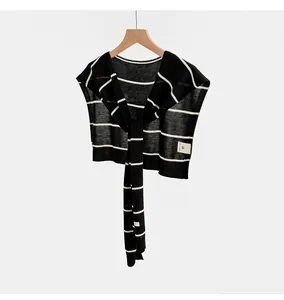 Primer plano de un chal de punto de Tencel a rayas blancas y negras colgado en una percha de madera