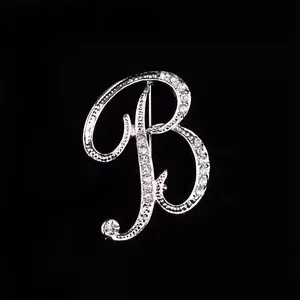 Primer plano detallado de un broche con la letra B plateada y diamantes de imitación