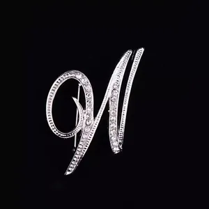 Primer plano de un elegante broche de letra plateada con incrustaciones de pedrería.