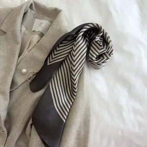 Close-up of geometric striped silk scarf styled on a grey herringbone blazer