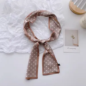 Detail view of a coffee brown polka dot skinny scarf tied in an elegant bow knot
