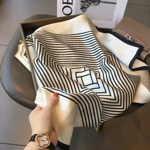 Detailed close-up of a premium black and white geometric silk scarf with smooth texture