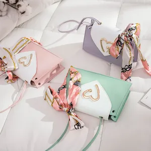 Close-up details of mini square bags with heart buckles and scarves in pastel colors