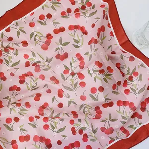 Nahaufnahme eines süßen Kirschmusters auf einem rosa Baumwoll-Leinen-Halstuch mit rotem Rand