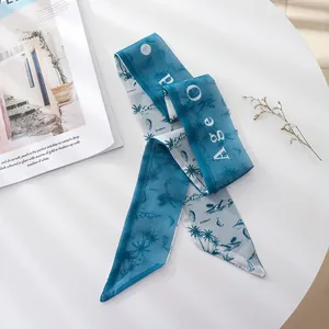 Close-up of a blue tropical print chiffon hair ribbon on a white table with a magazine.