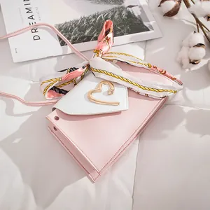 Close-up of pink mini crossbody bag with heart clasp and elegant silk scarf detail