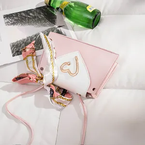 Detail view of pink mini square crossbody bag with gold heart clasp and silk scarf decoration