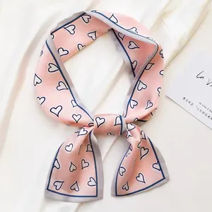 Close-up of a stylish pink silk skinny scarf with heart patterns on white fabric