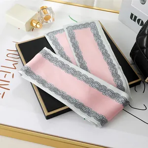 Close-up of pink silk scarf with lace border used as a stylish hair or bag accessory