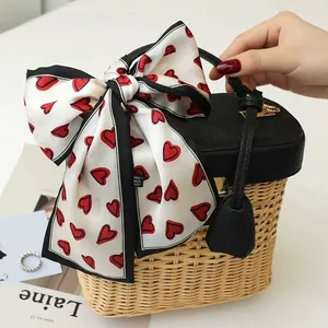 Close-up of a French retro silk scarf with red heart patterns tied to a basket bag
