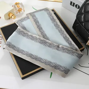 Detailed view of light blue silk scarf with elegant black floral lace border patterns