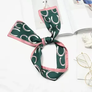 Detail view of the horseshoe pattern and pink trim on a vintage green silk scarf